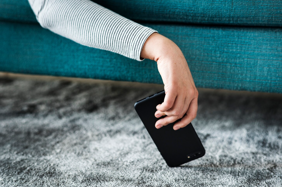 Hand letting go of a smartphone, symbolizing the need for a digital detox weekend.