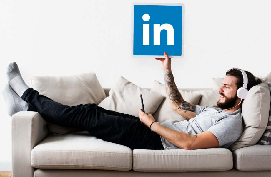 Man relaxing on a couch holding a LinkedIn logo, representing LinkedIn profile optimization.