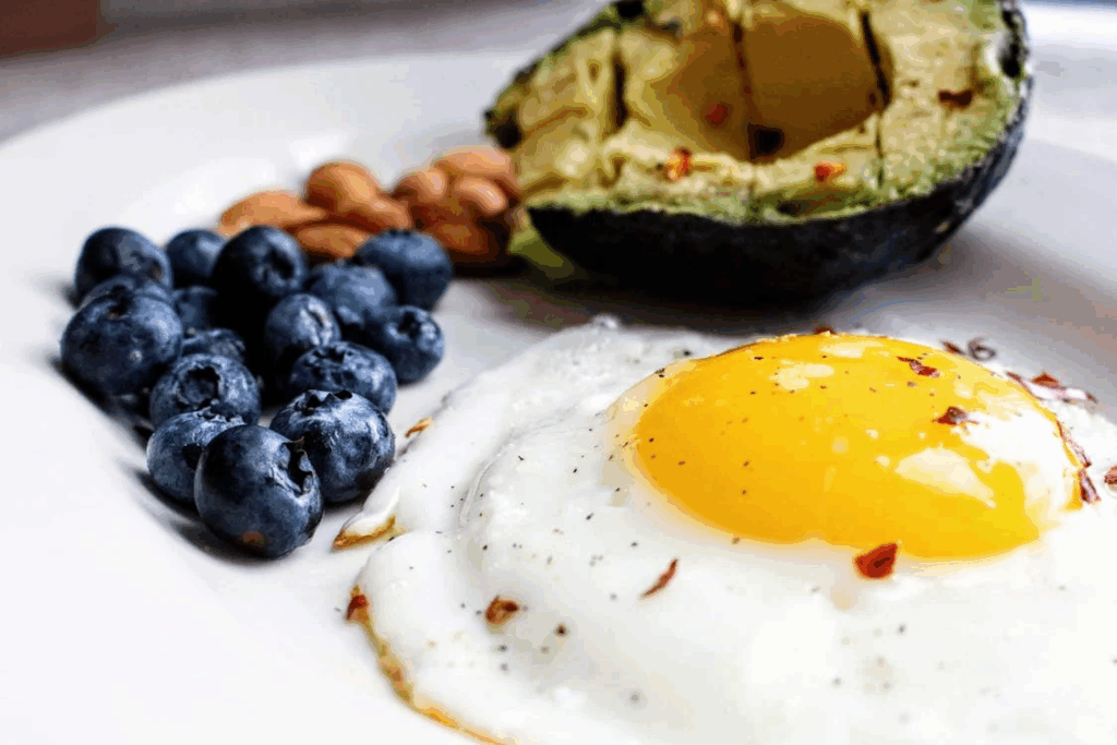 Plate with fried egg, avocado, and blueberries illustrating a mindful eating breakfast.