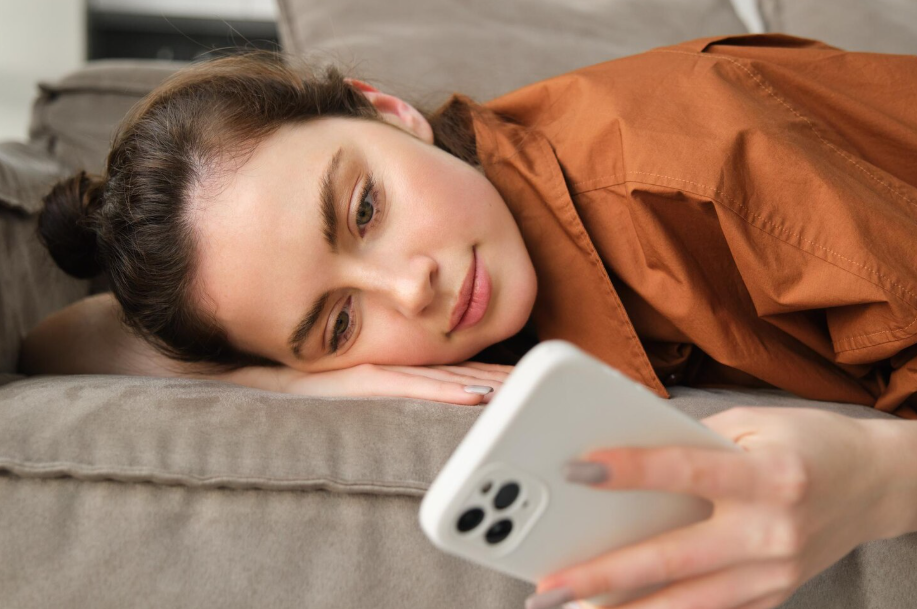 Woman lying on couch using her smartphone to log emotions in a mood tracking app