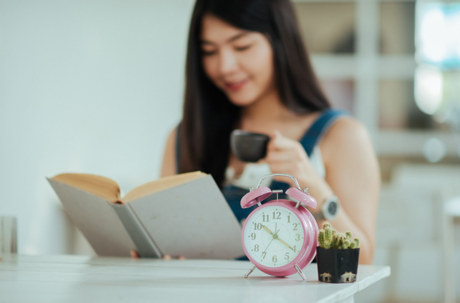 Calm morning routine featuring a pink alarm clock and woman reading