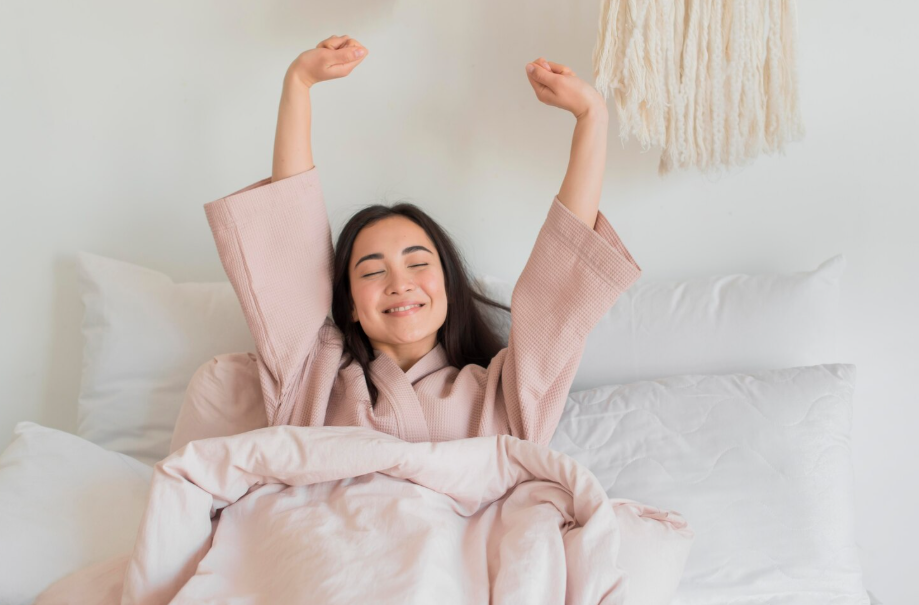 Woman stretching in bed after a good night’s sleep, illustrating better sleep quality