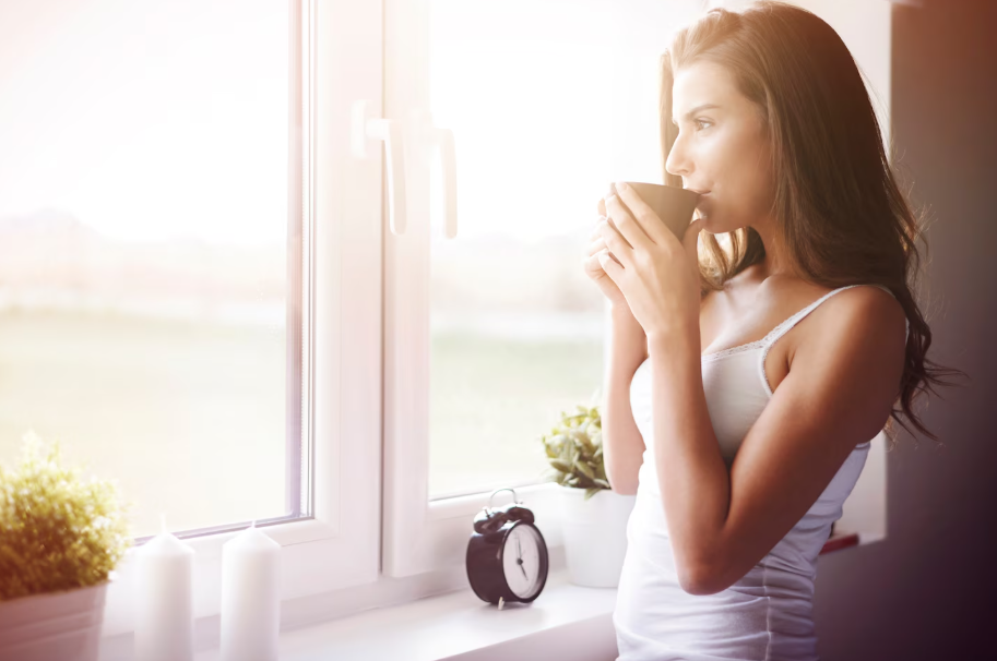Woman sipping tea by a sunny window, creating a micro-moment of joy